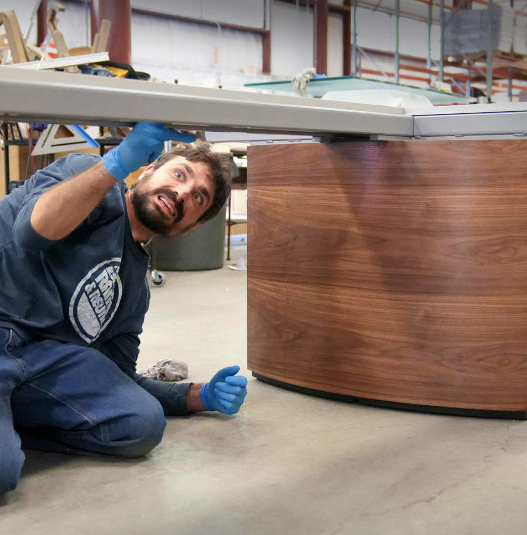 A Stoneline Designs fabricator puts the finishing touches on a conference table. Stoneline Designs executive office furniture is handcrafted in the USA.